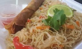 A pancit and egg roll lumpia meal with garnishes on top