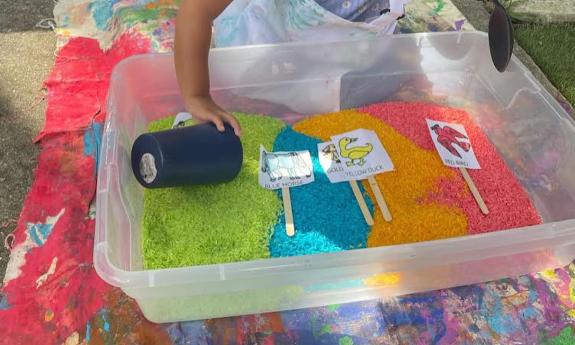 A child plays in a bin of colorful signs and sand