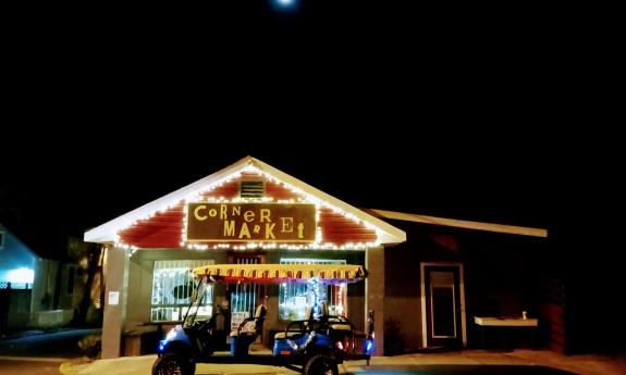 The blue Panda Tour electric golf cart, with a brightly-striped top sits in front of the Corner Market