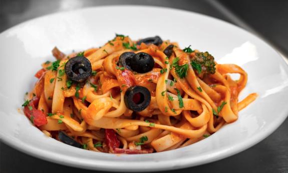 A bowl of pasta with garnishes sprinkled on top