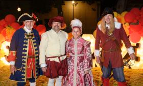 St. Augustine's Royal Family in front of an illuminated sign at the Spanish Food and Wine Festival