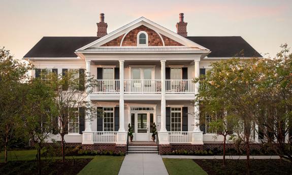 Twilight view the Markland Manor, which features white columns, double-stacked porches, and a prominent brick chimney