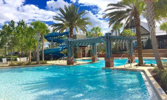 A resort-style swimming pool at RiverTown with an over-the-water pergola and a water slide