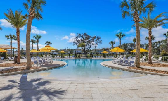 A spacious pool facility with lounge chairs and umbrellas on the deck