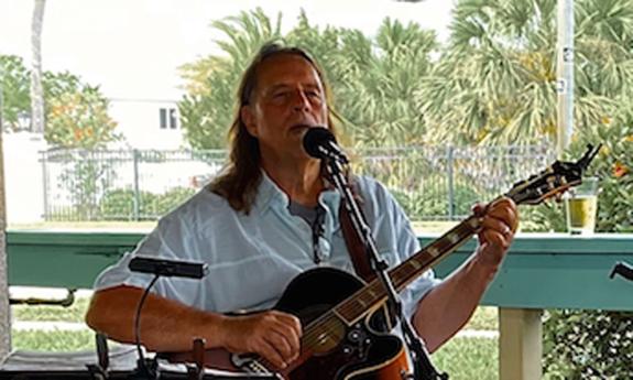 Musician David WAtt Besley, with guitar, onstage, outside