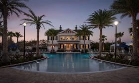 Dusk setting over the Markland Manor overlooking a swimming pool flanked by palm trees