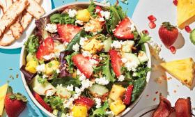 A bowl of salad filled with strawberries, cottage cheese, and pineapple