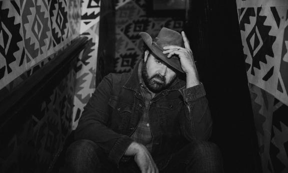 Randy Houser in black and white, sitting on stairs