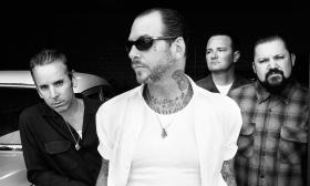 The four members of Social Distortion, standing against a black background