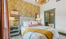 The bedroom in Apartment 1 at Three Stories Inn has warm tones with gold and green accents