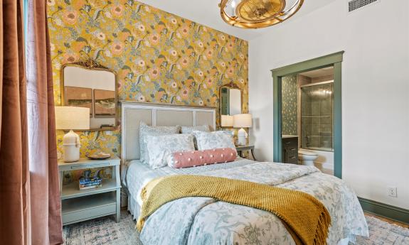 The bedroom in Apartment 1 at Three Stories Inn has warm tones with gold and green accents