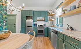 The large kitchen and dining area in Apartment 1 has green cabinets and wood accents