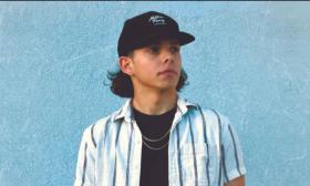 Singer-songwriter Cam Wheaton in blue ballcap and striped shirt in front of blue wall