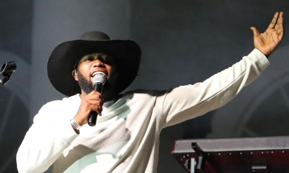 Singer songwriter Chris McNeil onstage with microphone, with arm raised