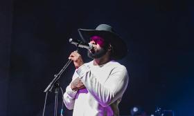 Singer songwriter Chris McNeil in black cowboy hat, singing into microphone