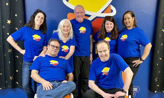 Improv performers pose in matching t-shirts on the Third Space Improv stage