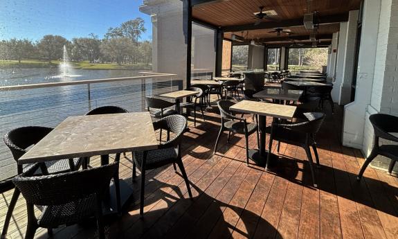 A back patio with additional tables and chairs overlooks the water