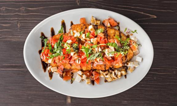 A bruschetta dish — tomatoes, mozzarella, red onion, basil, and balsamic glaze on top