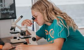 A young girl looks at water samples through a microscope while on board the boat