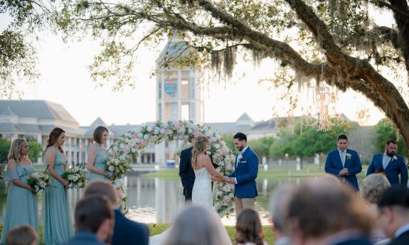 A bride and groom standing under a floral archway overlooking World Golf Village