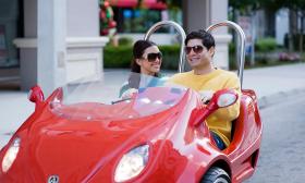 A smiling couple touring the city in a red scoot coupe