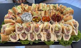 A catering of sandwiches with an assortment of toppings and condiments