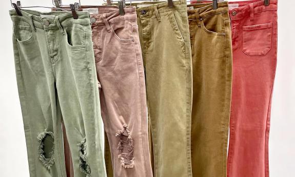 Various colored jeans hung up on a rack