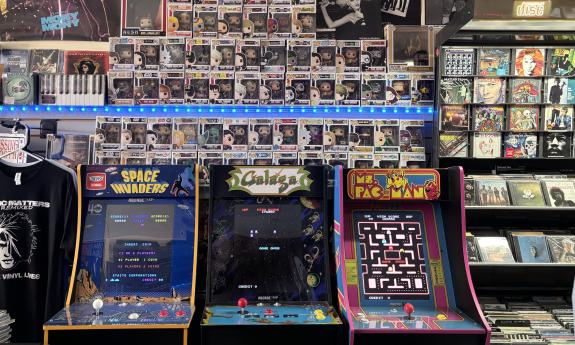 Retro arcade games with Funko Pops presented behind the machines