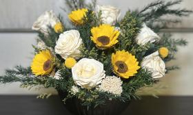 A vase of preserved sunflowers and white roses
