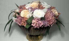 A large vase of preserved roses and hydrangeas