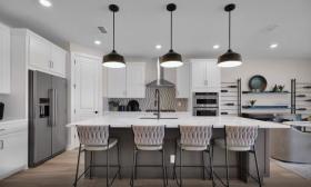 A kitchen with updated appliances and bright light fixtures