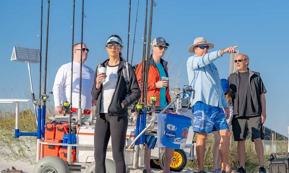 Fishing enthusiasts listen to Noel Kuhn, Surf Casting instructor on a sunny day at the beach