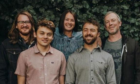 Headshot of AJ Lee & Blue Summit band in front of ivy covered wall