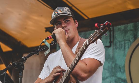 Musician Davis Cook onstage with microphone and guitar