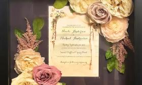 A shadowbox by Forever Blooms featuring preserved flowers and a wedding invitation