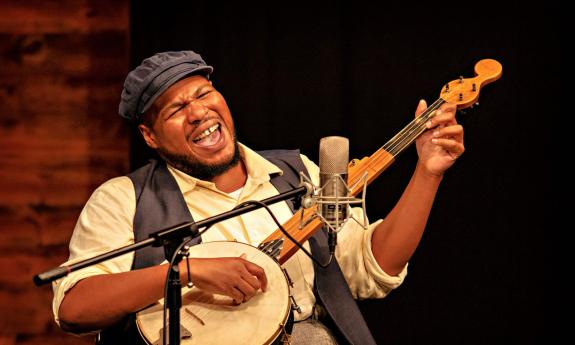 Blues great Jerron Paxton playing banjo and singing onstage.