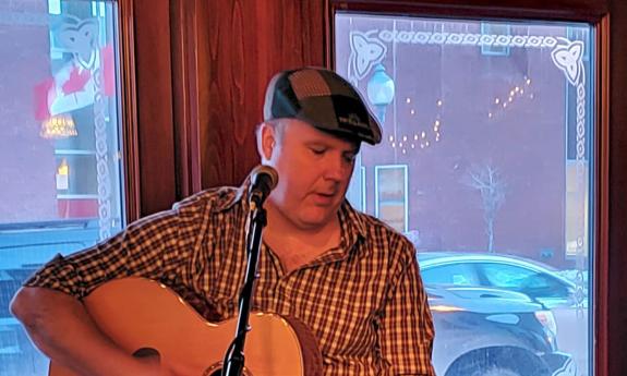 Performer and composer Jimmy Bragg singing, with his guitar