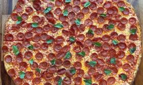 A pepperoni pizza with basil sprinkled on top