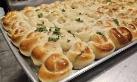 A pan of garlic knots with garnishes on top