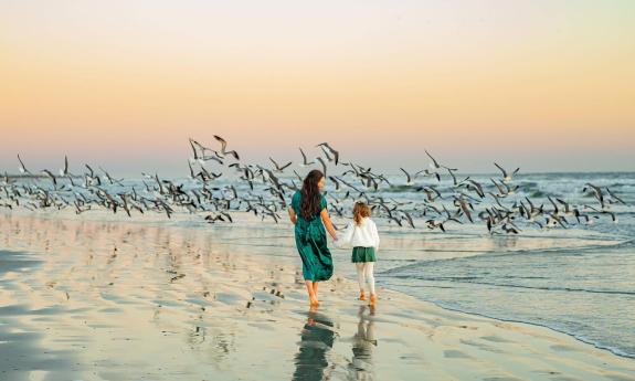 A mother and daughter walking on the beach