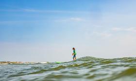 A child surfs the waves on a sunny day