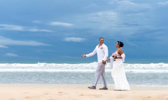 A couple walking hand-in-hand down the beach