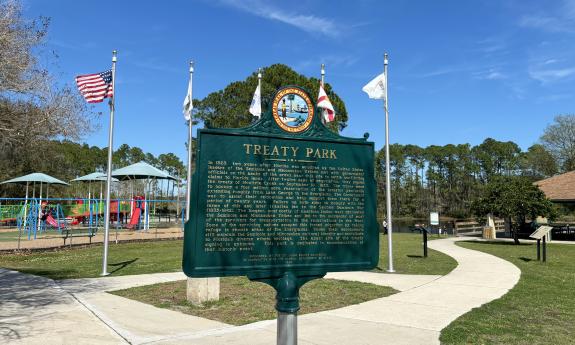 The Treaty Park plaque with flags flying in the background