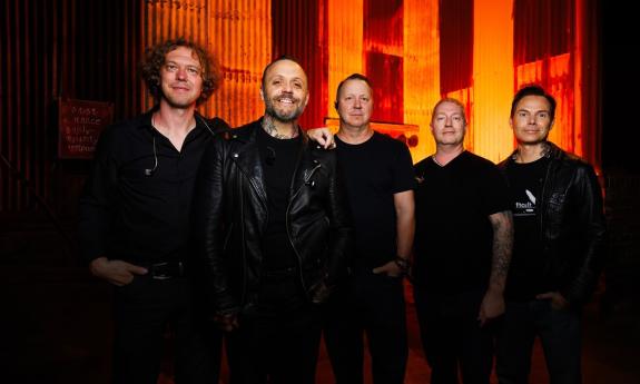 Bandmates from Blue October pose in front of an orange structure. 