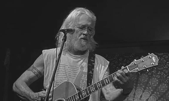 Mike Worrall playing his guitar in front of a microphone