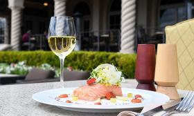 Salmon accompanied by a glass of white wine served on an outdoor table at Nineteen at TPC Sawgrass