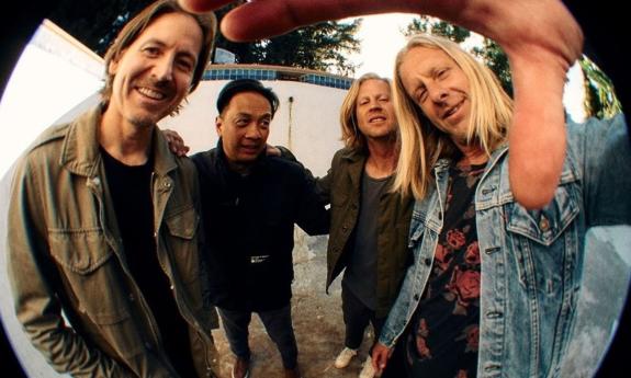 Bandmates from Switchfoot smile and pose in front of a fisheye lens. 