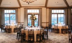 An indoor reception at TPC Sawgrass with set tables, large windows, and chandeliers