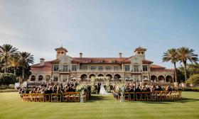 A wedding ceremony at TPC Sawgrass with guests seated on the lawn with the Mediterranean-style clubhouse in the background