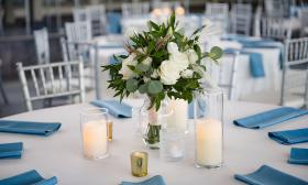 Dining decorations at The Yards featuring candles, blue napkins, and fresh flower arrangements
